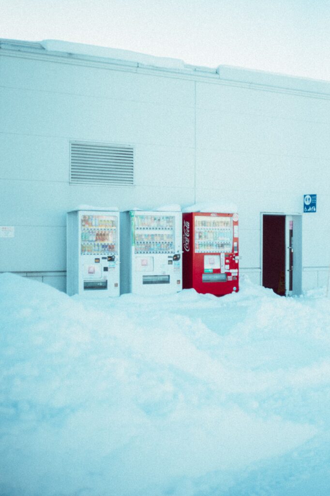 Three vending machines covered in snow outside a building in wintery Hokkaido, Japan.