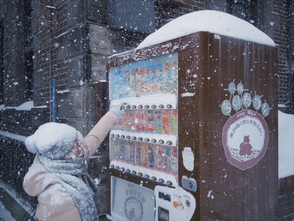 A person using a vending machine in a snowy Sapporo street winter scene.